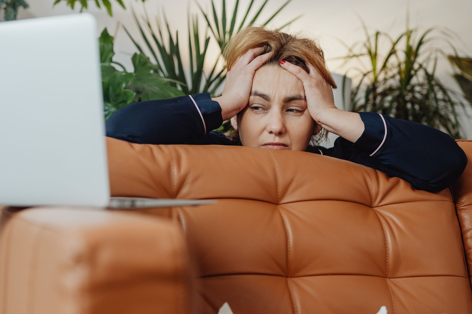 Mujer agotada con las manos en la cabeza frente al computador, imagen del burnout en mujeres con TDAH