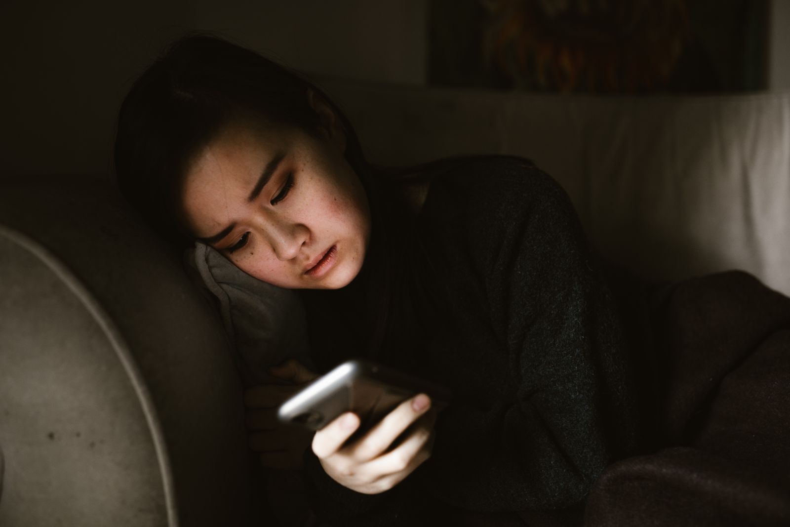 Mujer mirando el teléfono con expresión apagada, atrapada en la comparación con otras