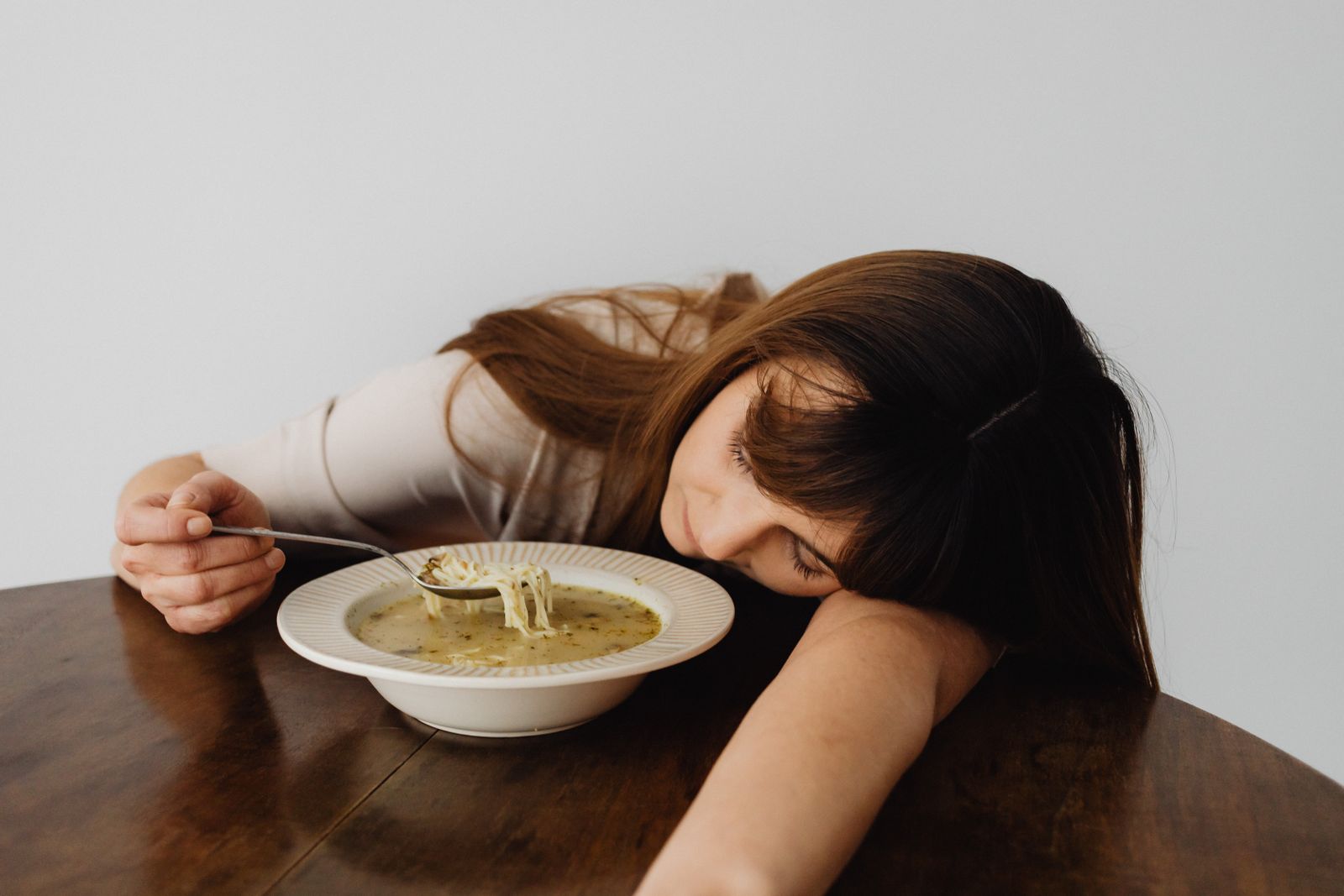 Mujer agotada con la cabeza apoyada en la mesa junto a un plato, imagen de la fatiga de decisión al final del día