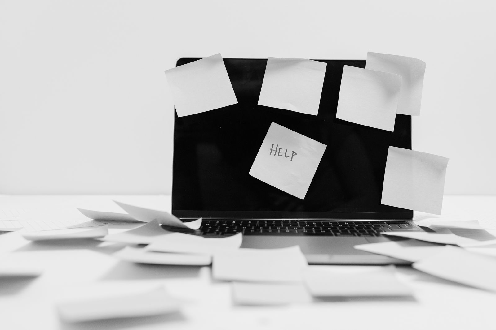Computador cubierto de notas adhesivas con la palabra ayuda, imagen de la lista invisible que nunca termina