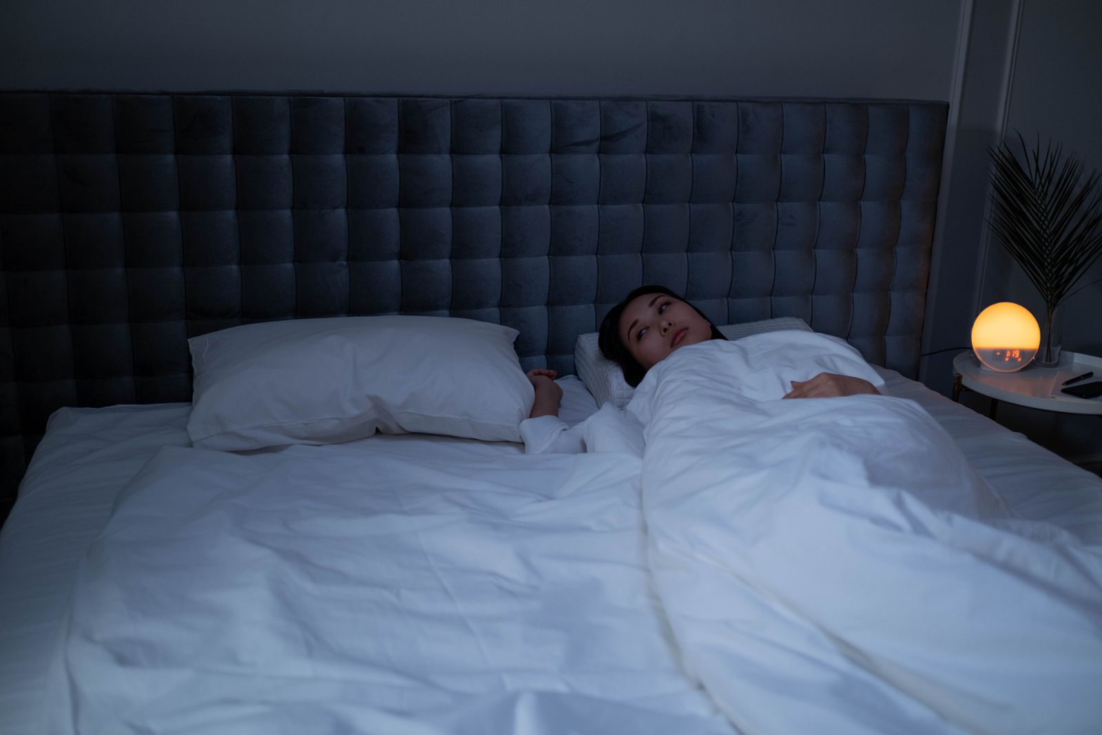Mujer despierta en la cama de noche, sin poder dormir repasando todo lo que le falta