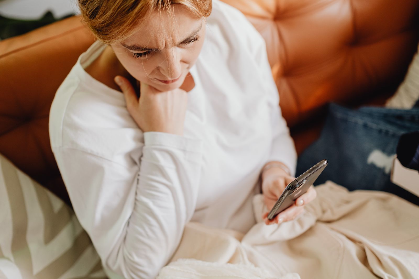 Mujer mirando el teléfono con preocupación por los mensajes que se le olvidó responder