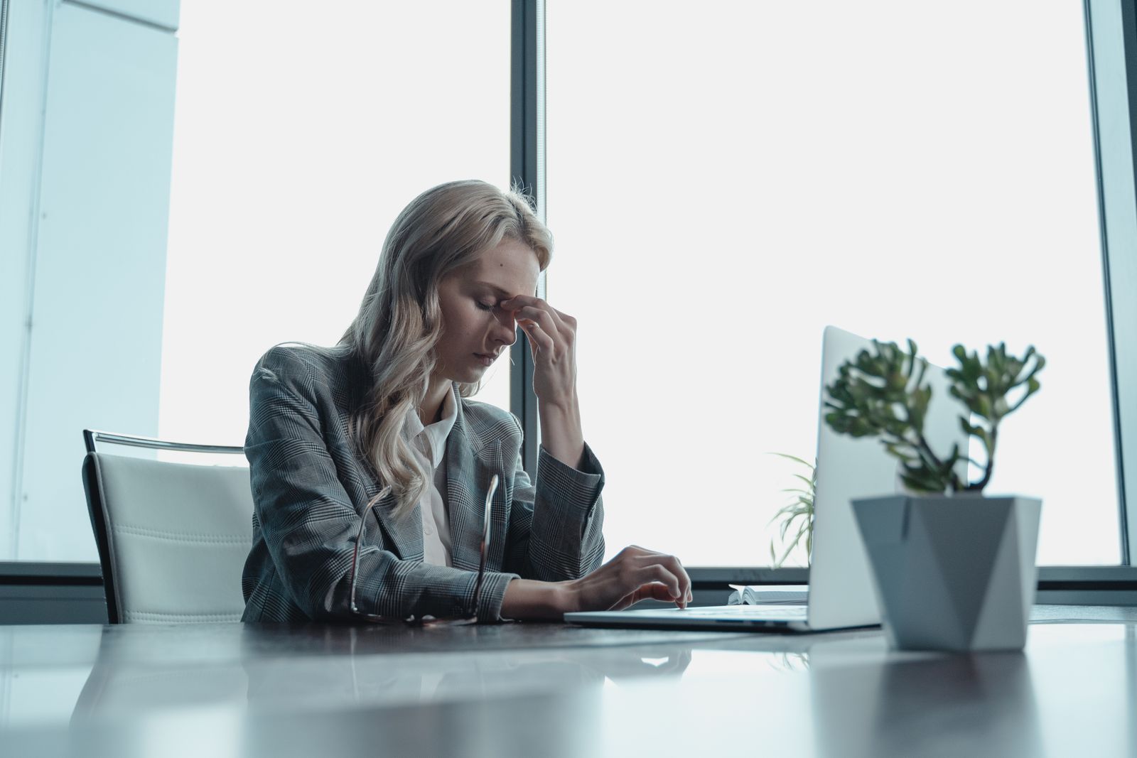 Mujer con la mano en la cabeza frente al computador tras una reunión, sin recordar qué acordó