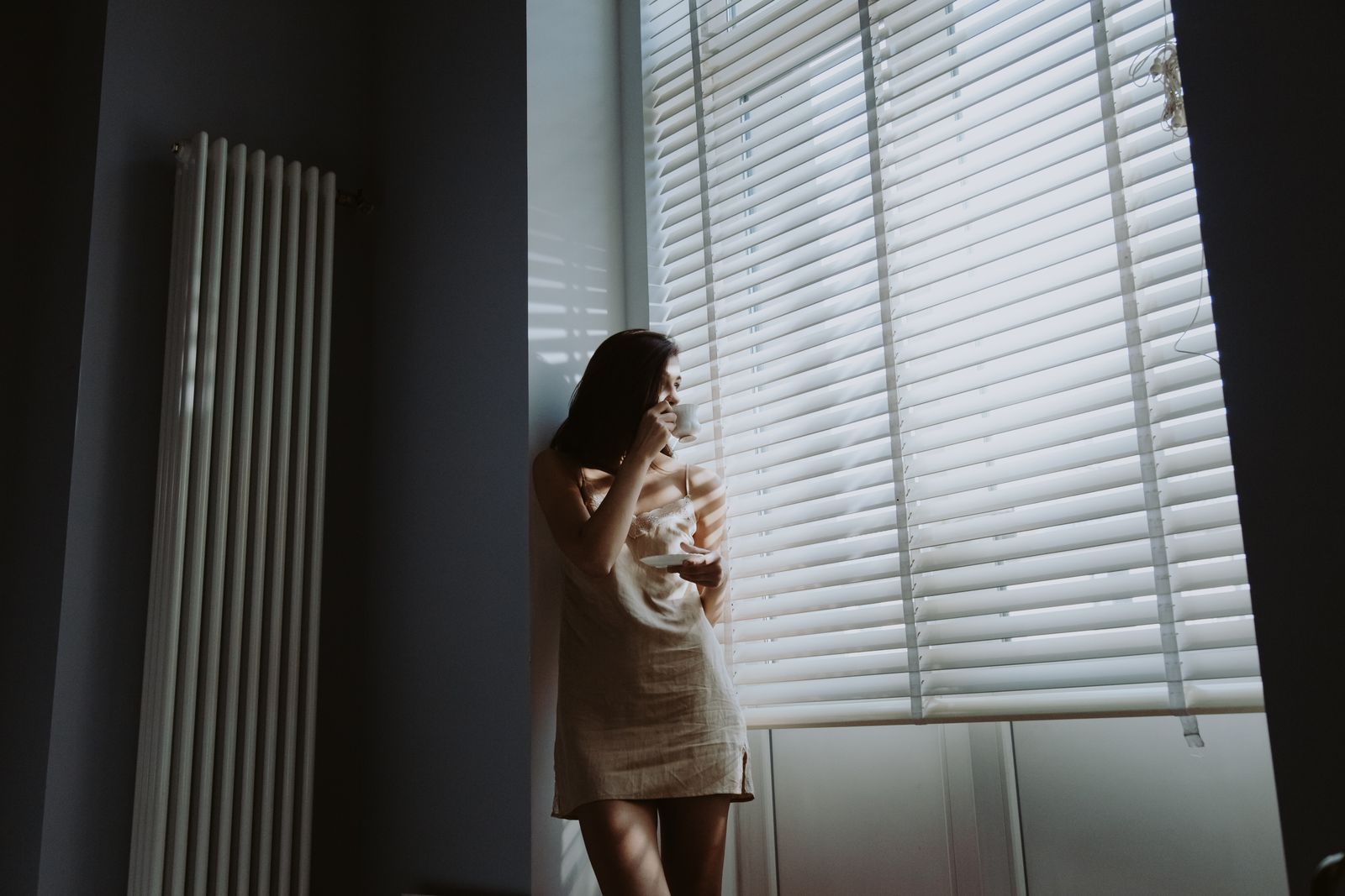 Mujer adulta pensativa junto a la ventana con una taza, reconociéndose en los síntomas de TDAH
