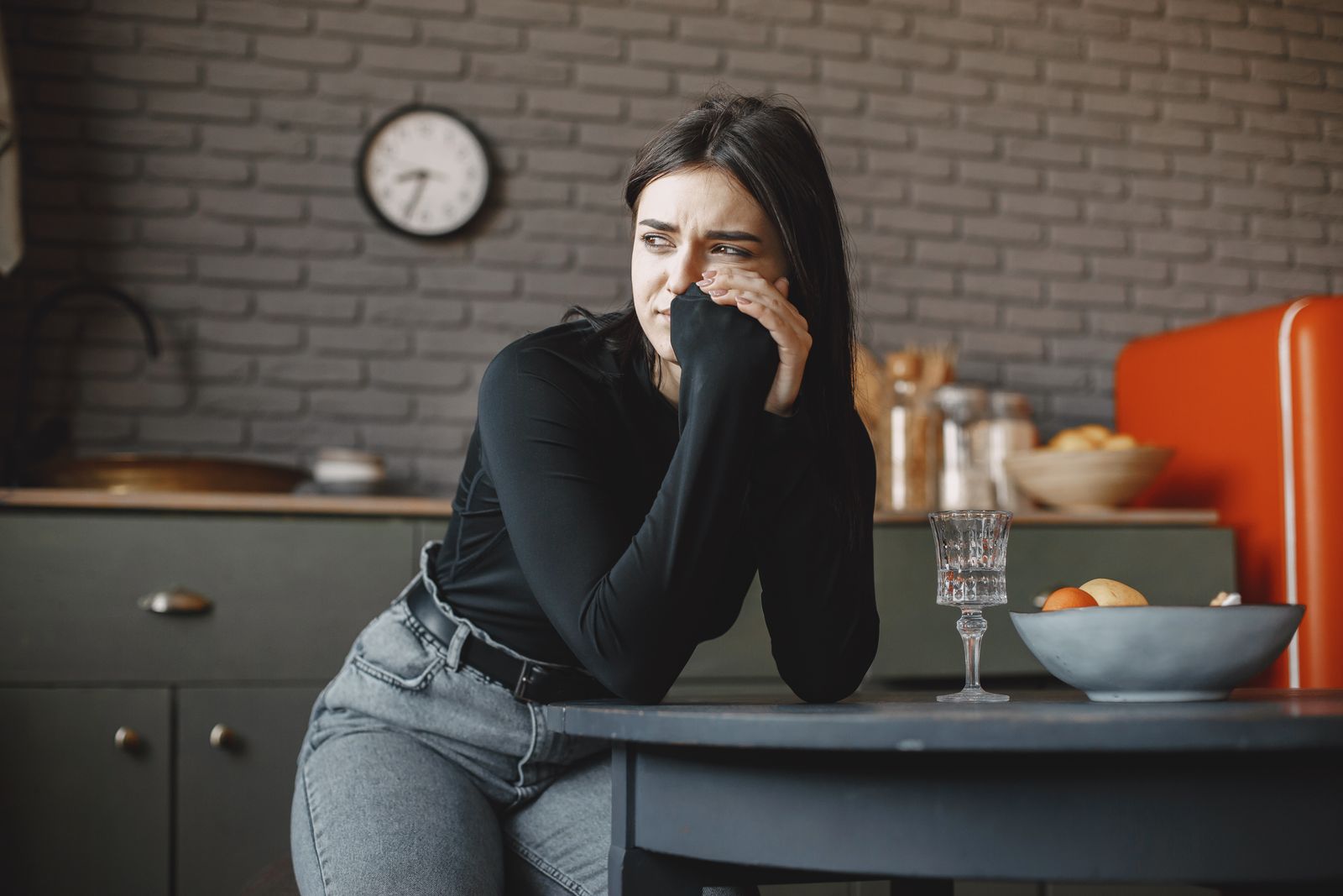Mujer preocupada apoyada en la mesa de la cocina, imagen de cómo el TDAH y la ansiedad vienen juntas