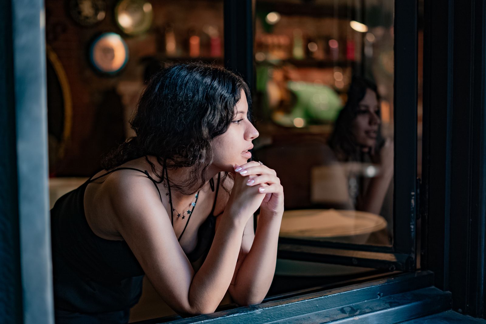 Mujer joven mirando por la ventana, perdida en sus pensamientos, una imagen del TDAH inatento en adultos