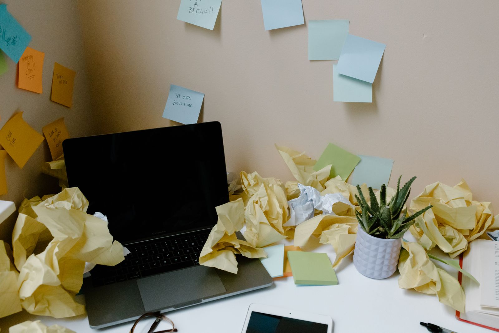 Desk buried under crumpled papers and sticky notes, a classic ADHD doom pile