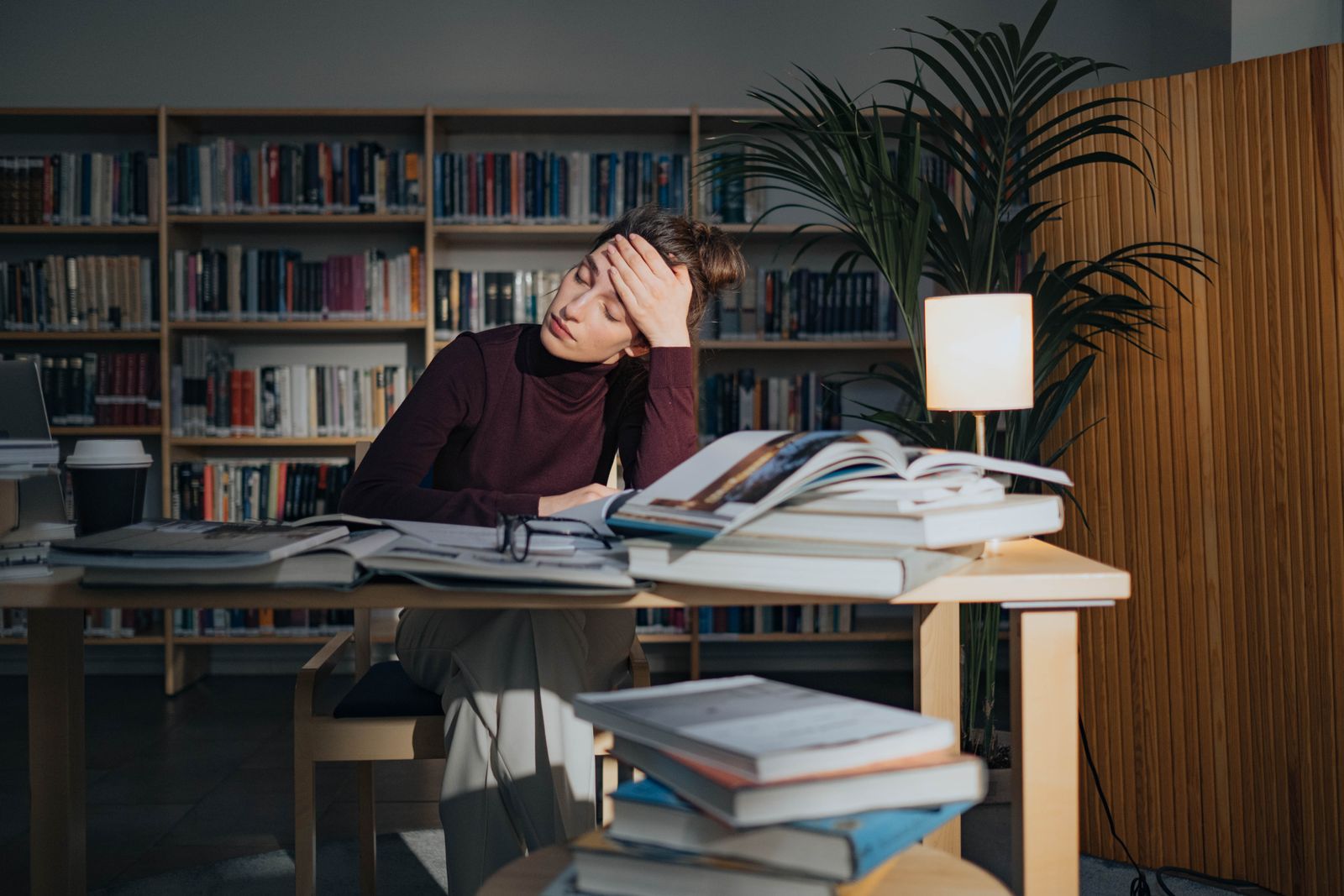 Tired woman surrounded by books, rereading a page she keeps forgetting, the ADHD reading retention struggle