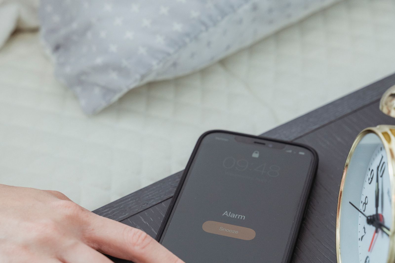 Hand reaching for a phone alarm, the ADHD reminder about to be snoozed